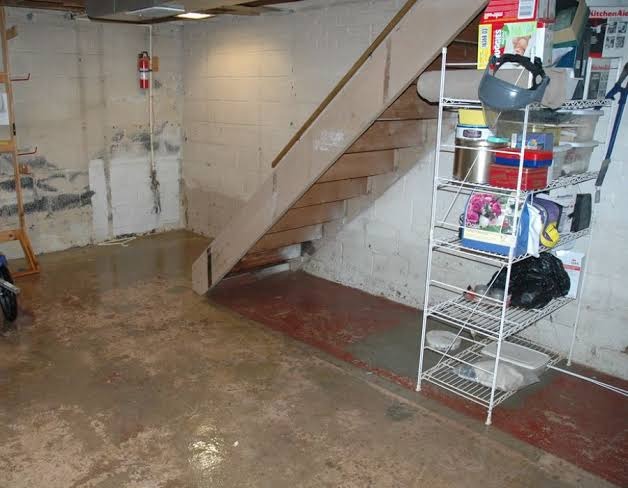 High water table intrusion on porous foundation slab with moisture staining under interior wooden staircase